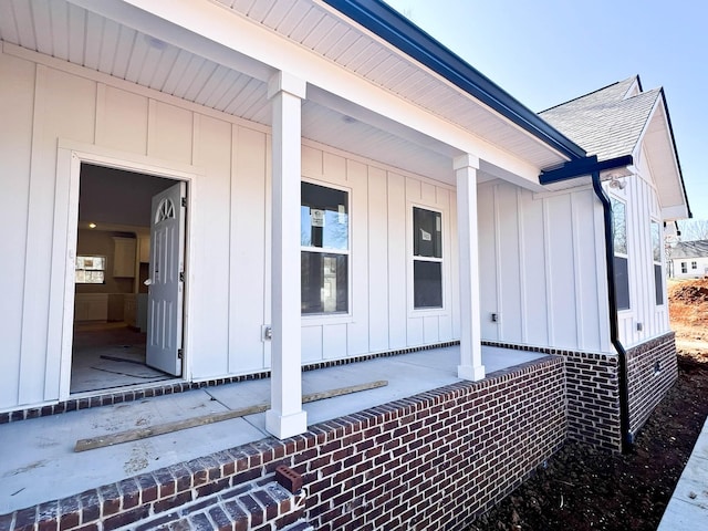 view of side of home with a shingled roof, a porch, and board and batten siding