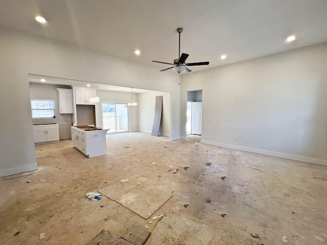 unfurnished living room featuring recessed lighting, baseboards, and ceiling fan with notable chandelier