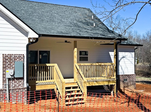 rear view of property with a shingled roof, covered porch, brick siding, and stairway