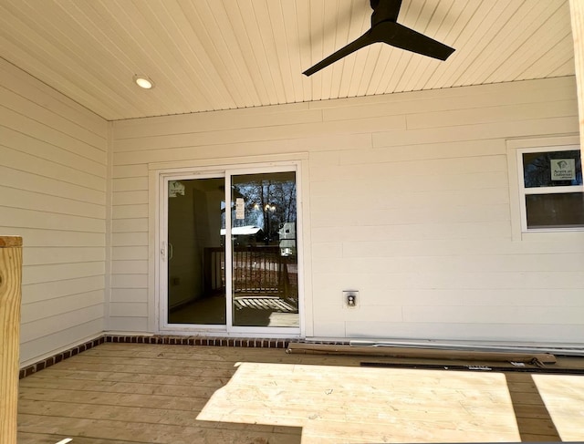 view of exterior entry with a ceiling fan and a wooden deck