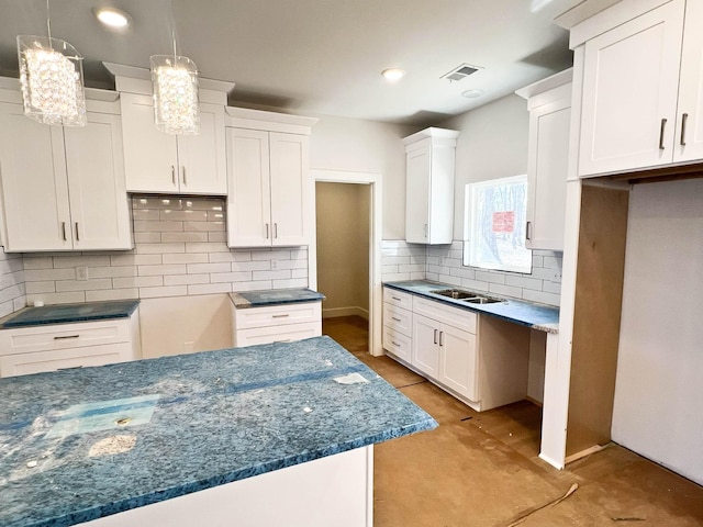 kitchen featuring decorative light fixtures, visible vents, backsplash, white cabinets, and dark stone countertops