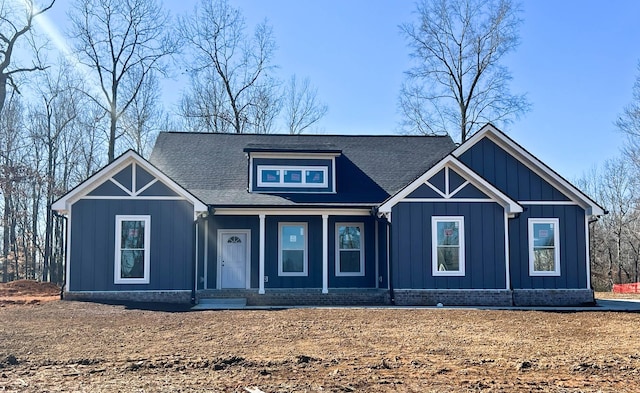 view of front facade featuring covered porch, a shingled roof, and board and batten siding