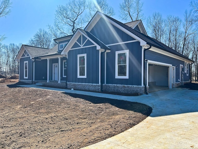 view of side of home with roof with shingles, covered porch, board and batten siding, a garage, and driveway