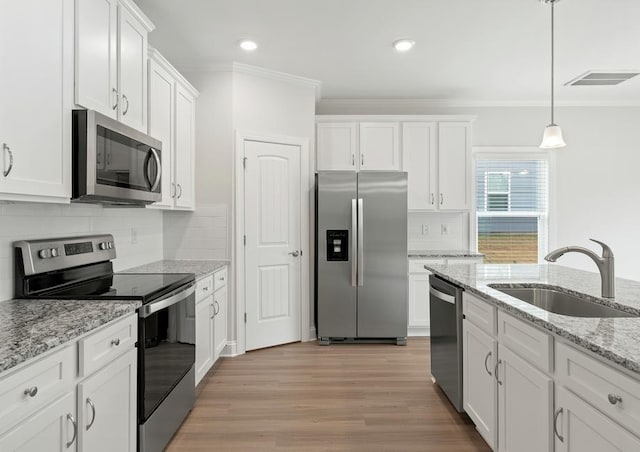 kitchen with sink, white cabinets, hanging light fixtures, and appliances with stainless steel finishes