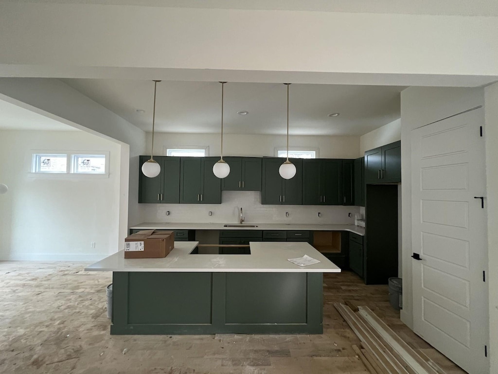 kitchen with tasteful backsplash, sink, a kitchen island, and pendant lighting