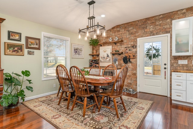 dining space featuring a wealth of natural light, brick wall, dark hardwood / wood-style floors, and a notable chandelier