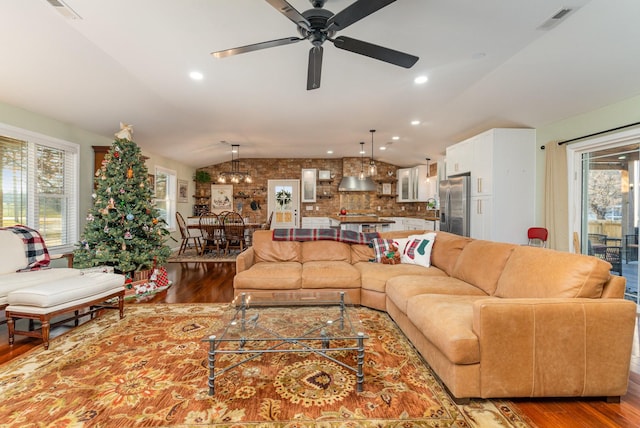 living room with hardwood / wood-style flooring, vaulted ceiling, and ceiling fan