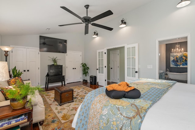 bedroom with wood-type flooring, ceiling fan with notable chandelier, ensuite bathroom, and lofted ceiling