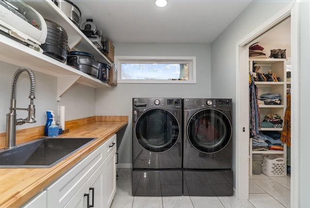 laundry area featuring washer and dryer, light tile patterned floors, and sink