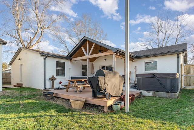 rear view of property featuring a lawn, a hot tub, and a deck