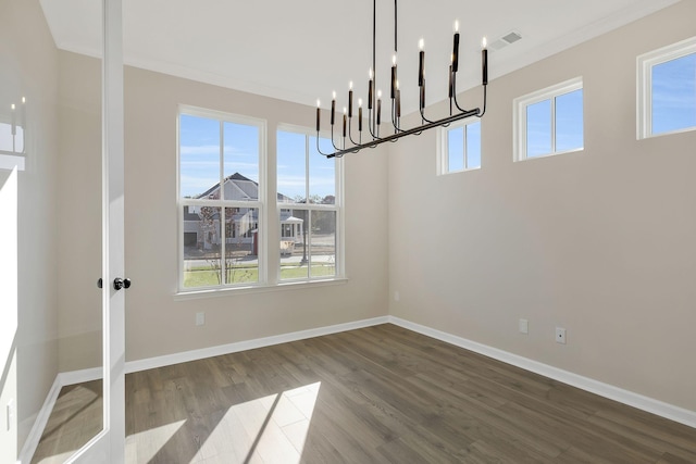 unfurnished dining area with hardwood / wood-style flooring, crown molding, plenty of natural light, and a notable chandelier