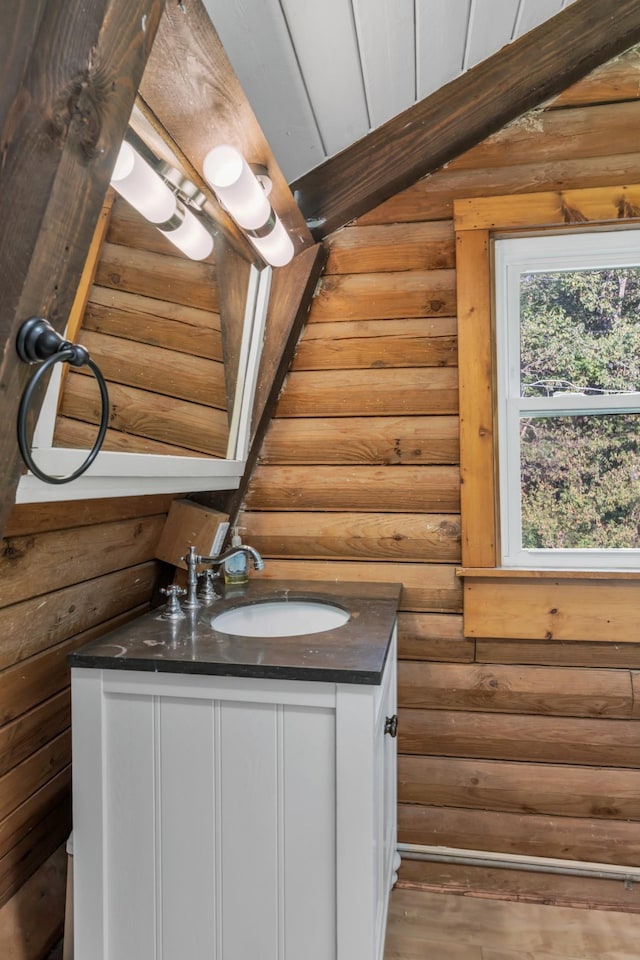 bathroom with wood-type flooring, vanity, and rustic walls