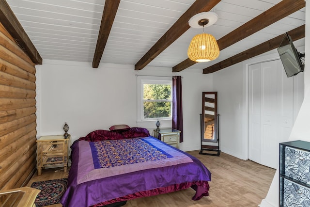 bedroom with lofted ceiling with beams and light hardwood / wood-style floors