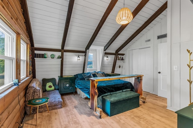 bedroom featuring wooden walls, light hardwood / wood-style flooring, and beamed ceiling