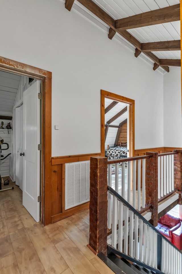 hallway with wooden walls, lofted ceiling with beams, light wood-type flooring, and wood ceiling