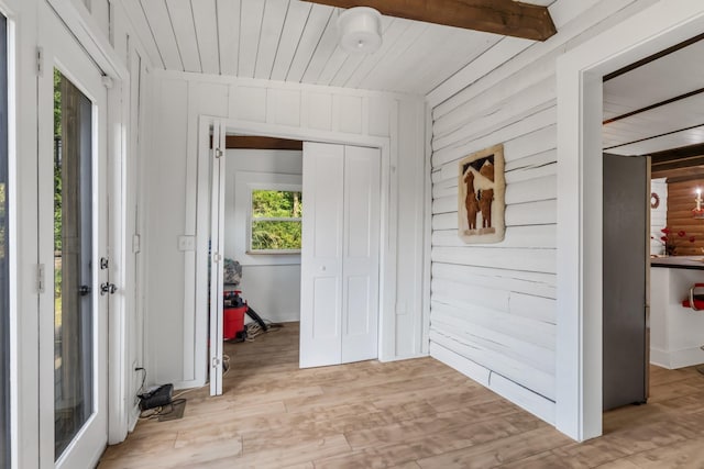 hall featuring wood walls, wood ceiling, beam ceiling, and light hardwood / wood-style flooring