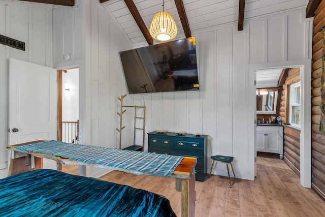 bedroom featuring vaulted ceiling with beams and light hardwood / wood-style flooring