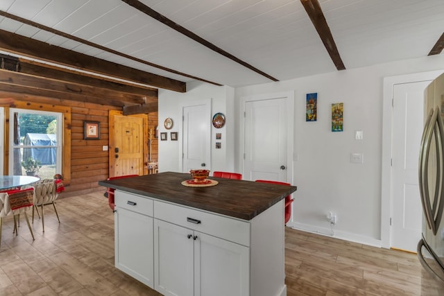 kitchen featuring a center island, white cabinets, light wood-type flooring, butcher block countertops, and beam ceiling