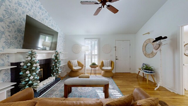 living room with ceiling fan, light hardwood / wood-style floors, and vaulted ceiling