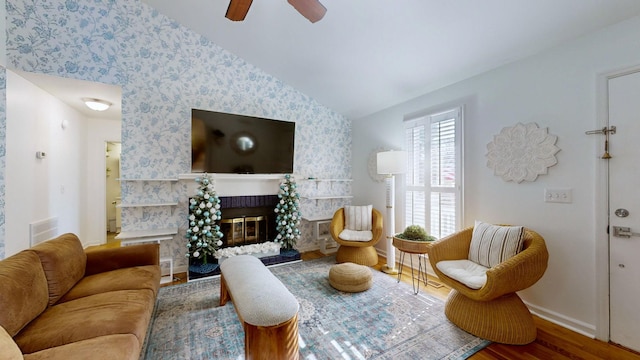 living room with a fireplace, hardwood / wood-style flooring, vaulted ceiling, and ceiling fan