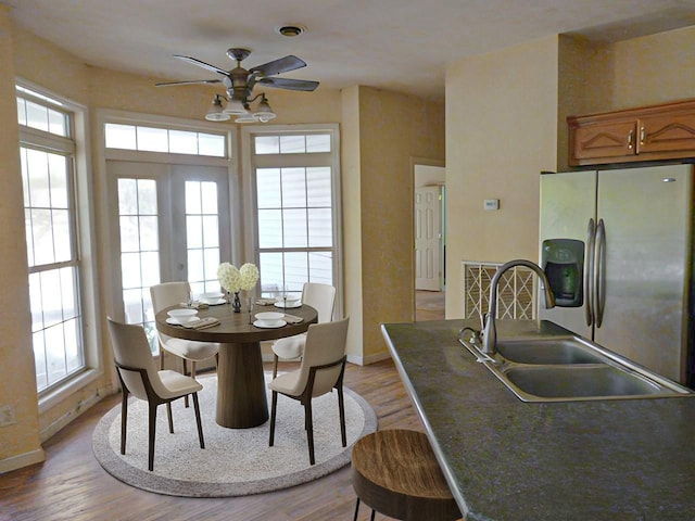 dining room with ceiling fan, light wood-type flooring, sink, and french doors