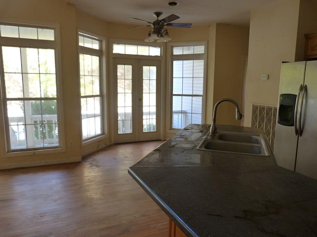 kitchen featuring french doors, sink, ceiling fan, white fridge with ice dispenser, and wood-type flooring