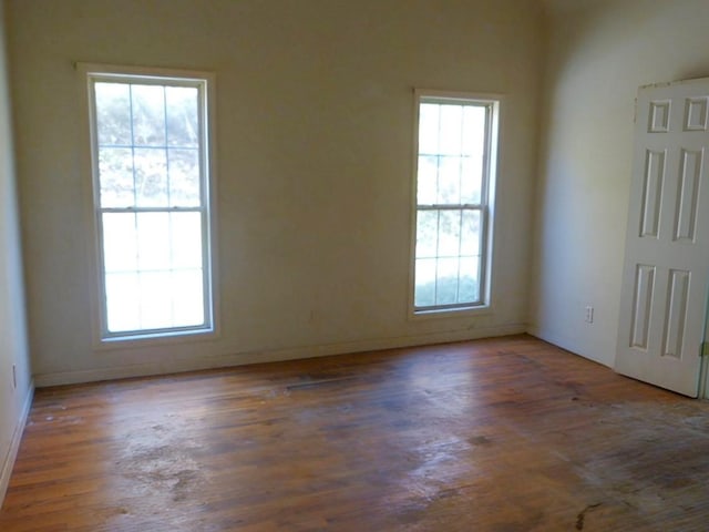 unfurnished room featuring dark wood-type flooring and a healthy amount of sunlight