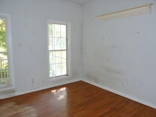 spare room with dark hardwood / wood-style flooring and a healthy amount of sunlight