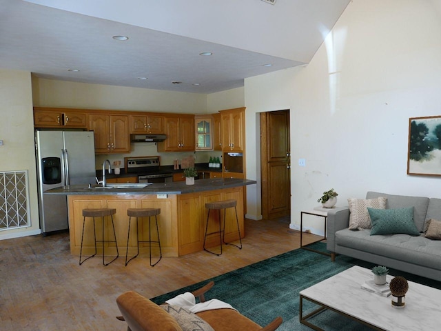 kitchen featuring a center island with sink, stainless steel appliances, a breakfast bar area, and hardwood / wood-style floors