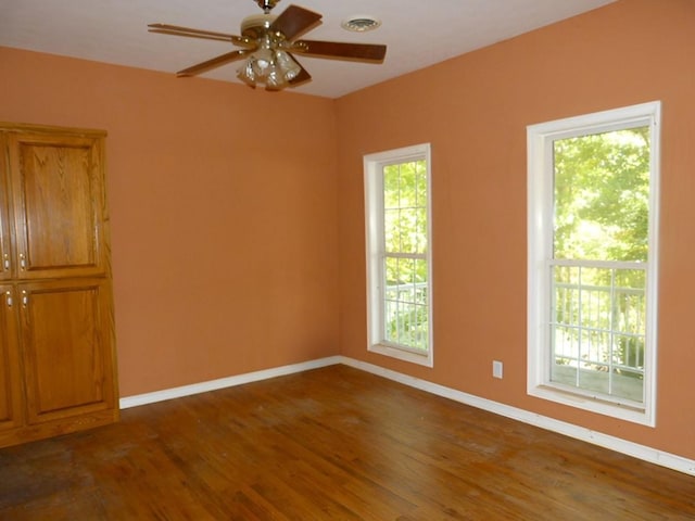 unfurnished room featuring plenty of natural light, ceiling fan, and dark hardwood / wood-style flooring