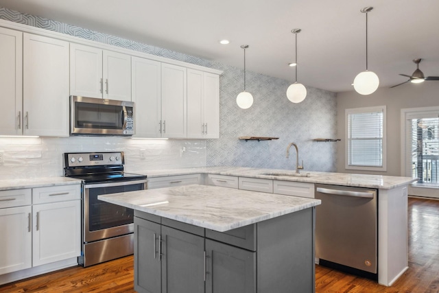 kitchen with white cabinets, a kitchen island, stainless steel appliances, and a sink