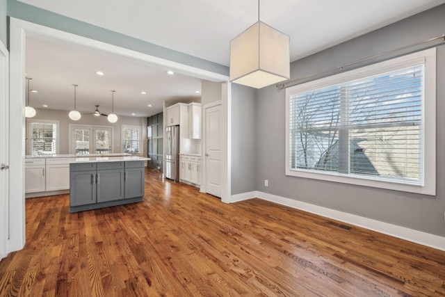 kitchen featuring gray cabinetry, white cabinets, hanging light fixtures, stainless steel fridge, and dark hardwood / wood-style flooring