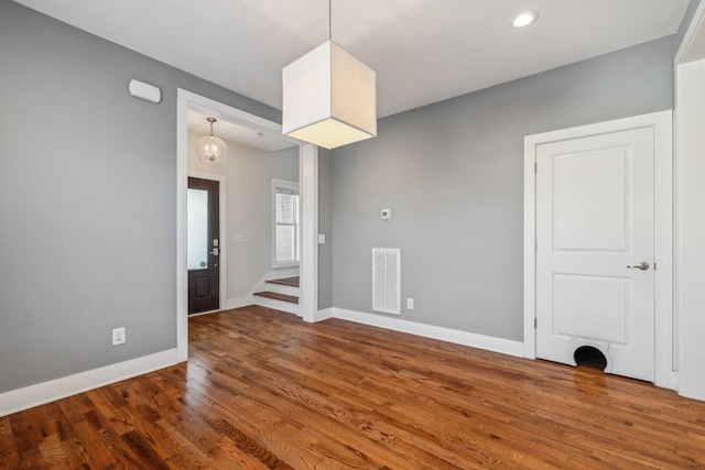 unfurnished room with stairs, visible vents, baseboards, and wood finished floors