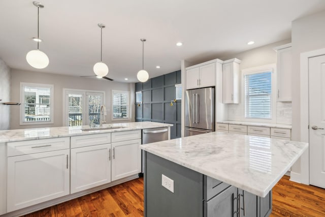 kitchen with sink, dark hardwood / wood-style floors, an island with sink, white cabinets, and appliances with stainless steel finishes