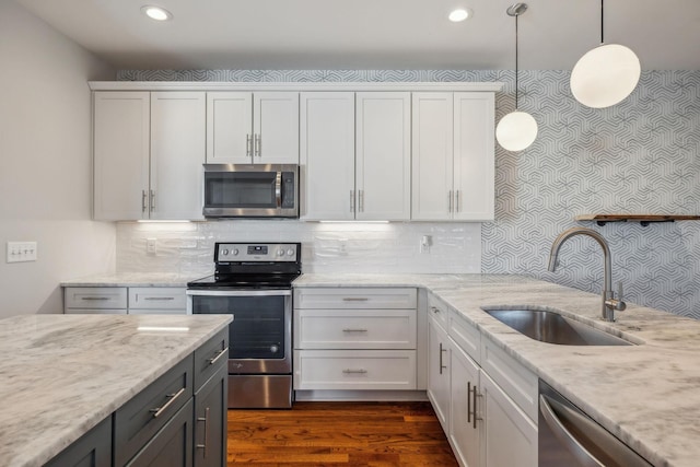 kitchen with decorative light fixtures, sink, white cabinetry, and stainless steel appliances