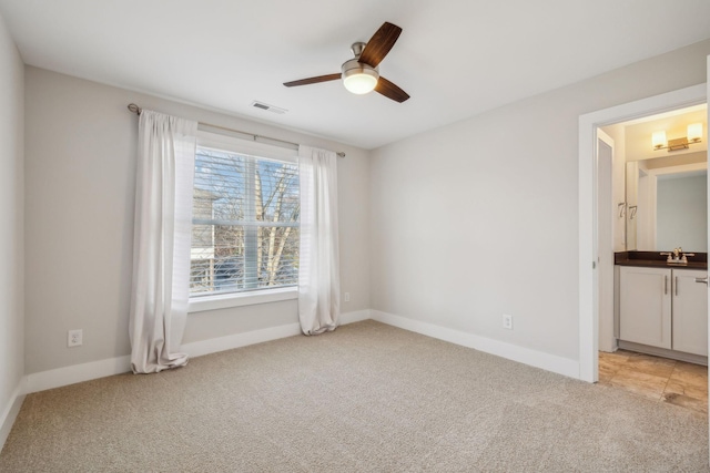 unfurnished bedroom featuring light colored carpet, visible vents, a sink, and baseboards