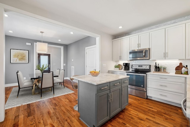 kitchen featuring gray cabinetry, stainless steel appliances, a kitchen island, white cabinets, and decorative light fixtures