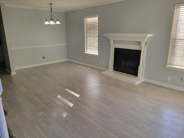 unfurnished living room featuring a fireplace, light hardwood / wood-style flooring, a chandelier, and ornamental molding