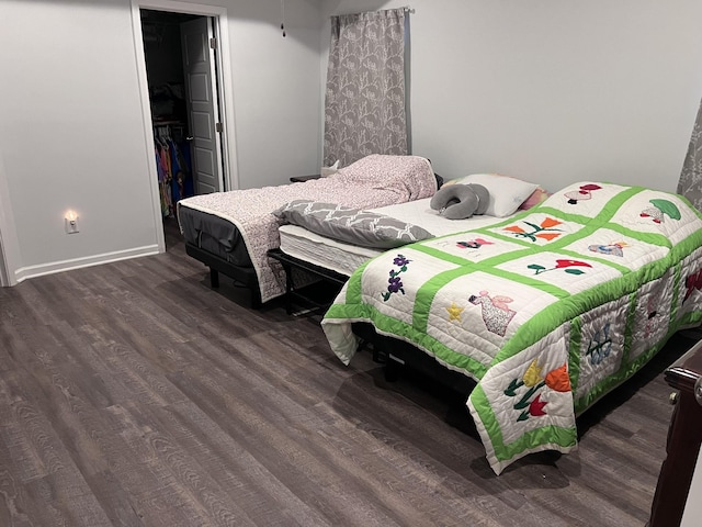 bedroom with a walk in closet, dark hardwood / wood-style floors, and a closet