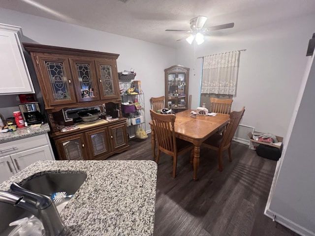 dining room featuring ceiling fan, sink, and dark wood-type flooring