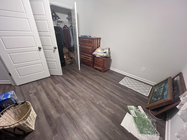 bedroom with dark hardwood / wood-style floors and a closet