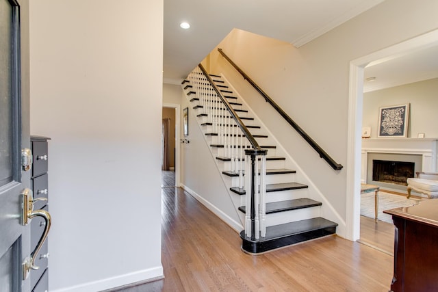 stairs with hardwood / wood-style floors and ornamental molding