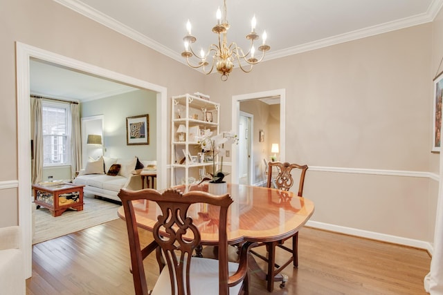 dining room with a chandelier, light wood-type flooring, and crown molding