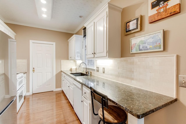 kitchen with crown molding, sink, dark stone countertops, white cabinets, and light hardwood / wood-style floors