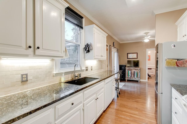 kitchen featuring white cabinets, stainless steel refrigerator, and sink