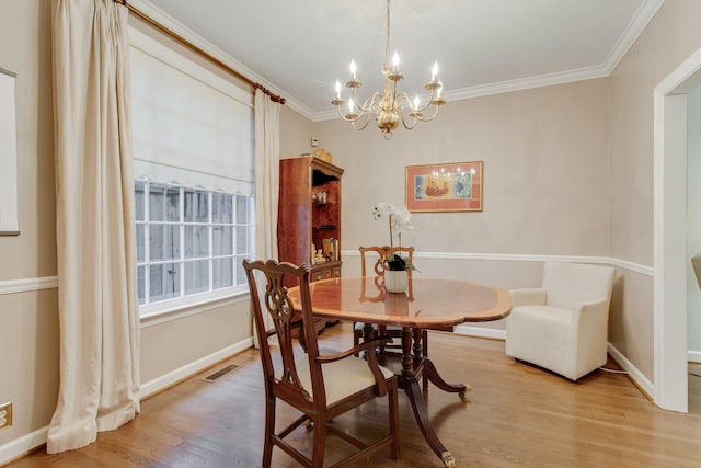 dining space featuring ornamental molding, light hardwood / wood-style flooring, and a notable chandelier