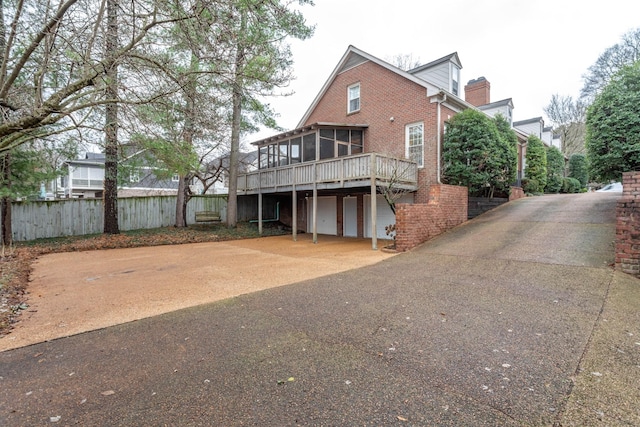 back of house with a sunroom, a garage, and a deck