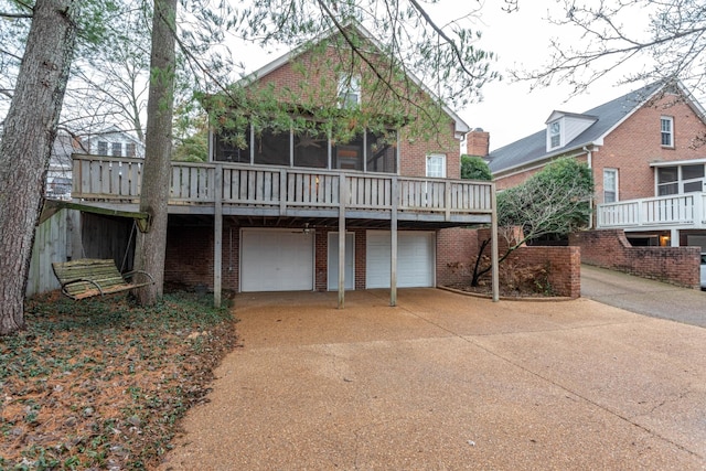 back of property featuring a wooden deck, a sunroom, and a garage