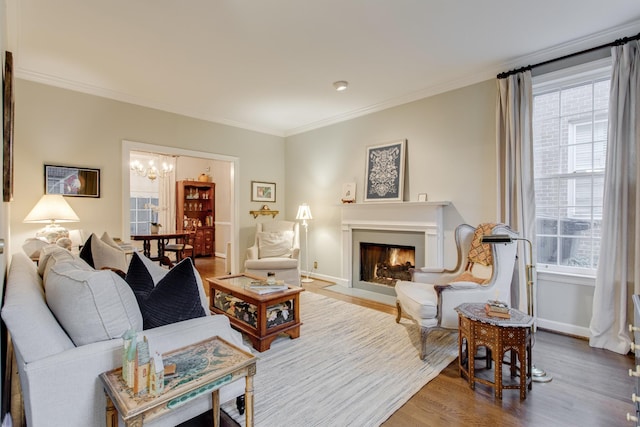 living room featuring ornamental molding, a healthy amount of sunlight, a notable chandelier, and hardwood / wood-style flooring