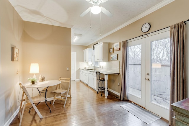 dining space with light wood-type flooring, sink, and ornamental molding